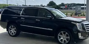 A black car parked in the driveway of a house.